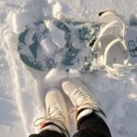 A Person in Black Pants and White Shoes Standing on Snow Covered Ground