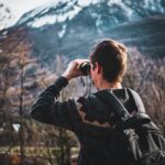 Man Using Black Binoculars Near Forest Trees at Daytime