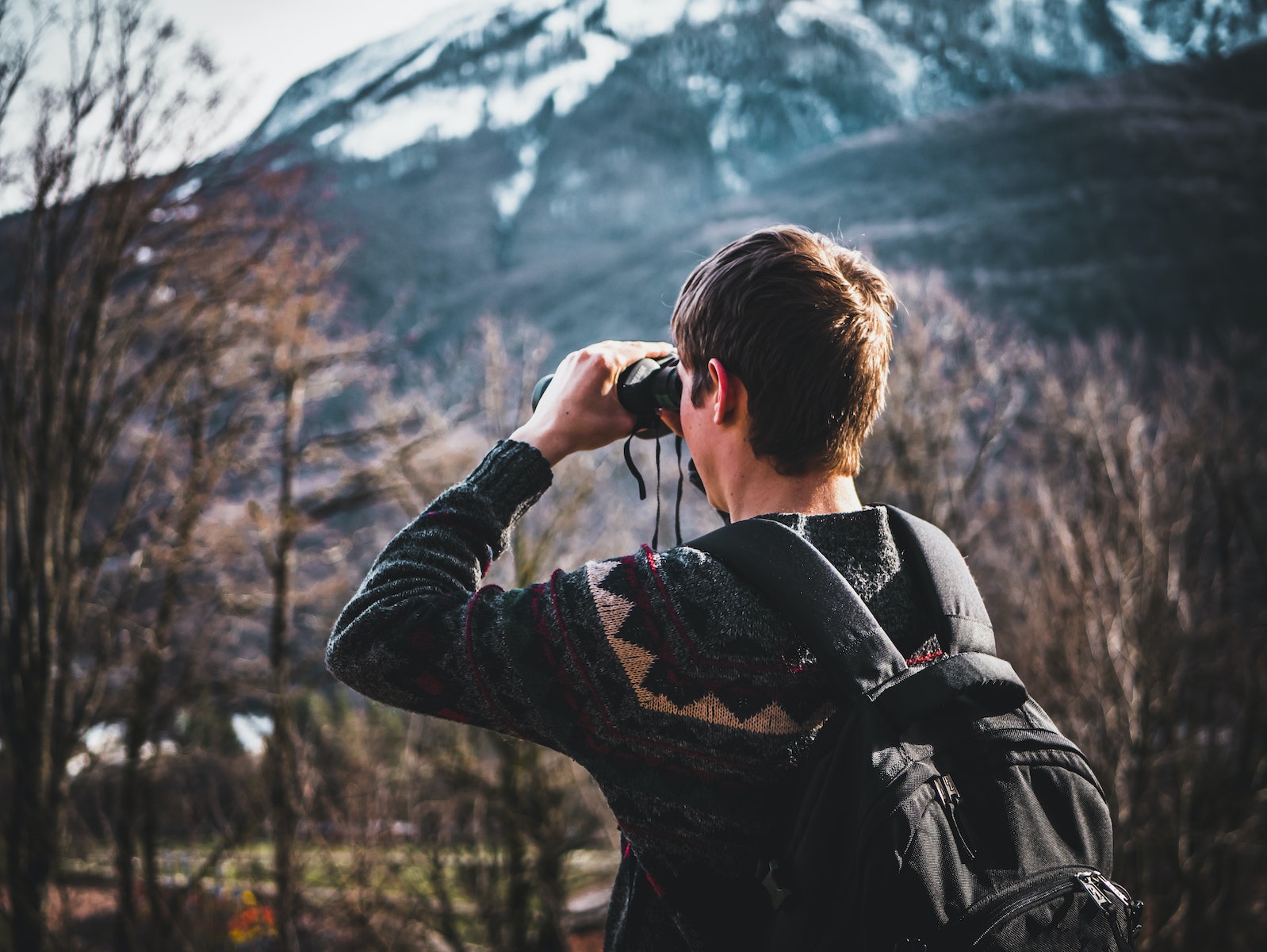 Man Using Black Binoculars Near Forest Trees at Daytime