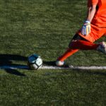 man kicking soccer ball on field