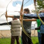 three person practicing using arrow