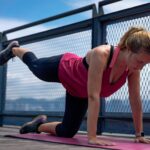 woman in red tank top and black leggings doing yoga