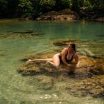 woman in black bikini lying on water during daytime