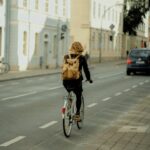 woman in black jacket riding bicycle on road during daytime