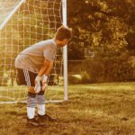 boy standing on soccer goal net