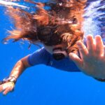 woman in white and blue floral bikini top and blue denim jeans under water